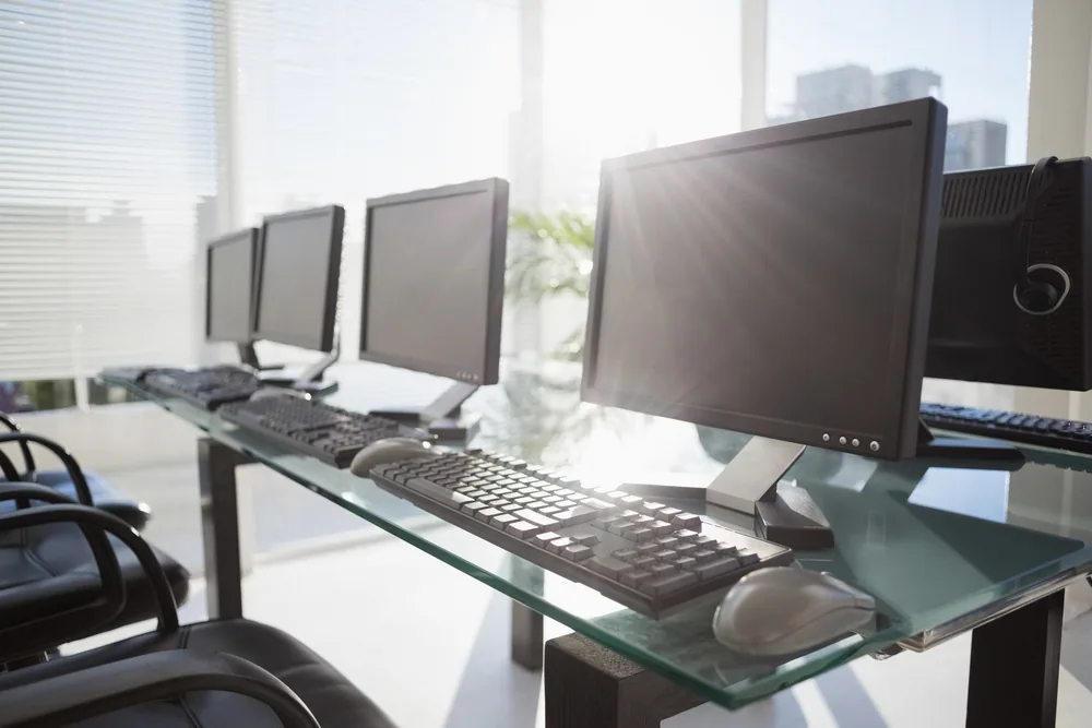 Monitores, teclados y ratones alineados en los puestos de una oficina