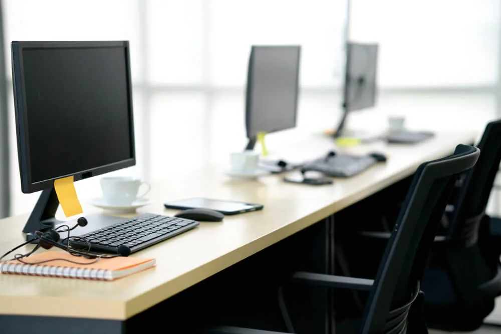 Mesa de oficina con monitores apagados, teclado y ratón