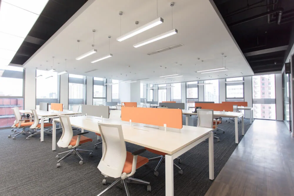 Oficina diáfana con mamparas naranjas y puestos de trabajo vacíos