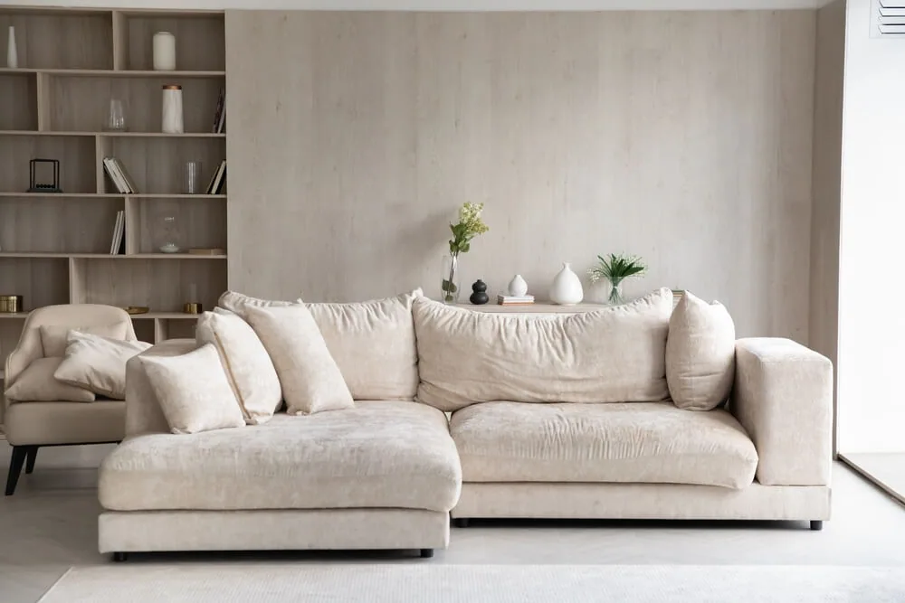 Salón con sofá chaise longue, butaca y estantería de madera