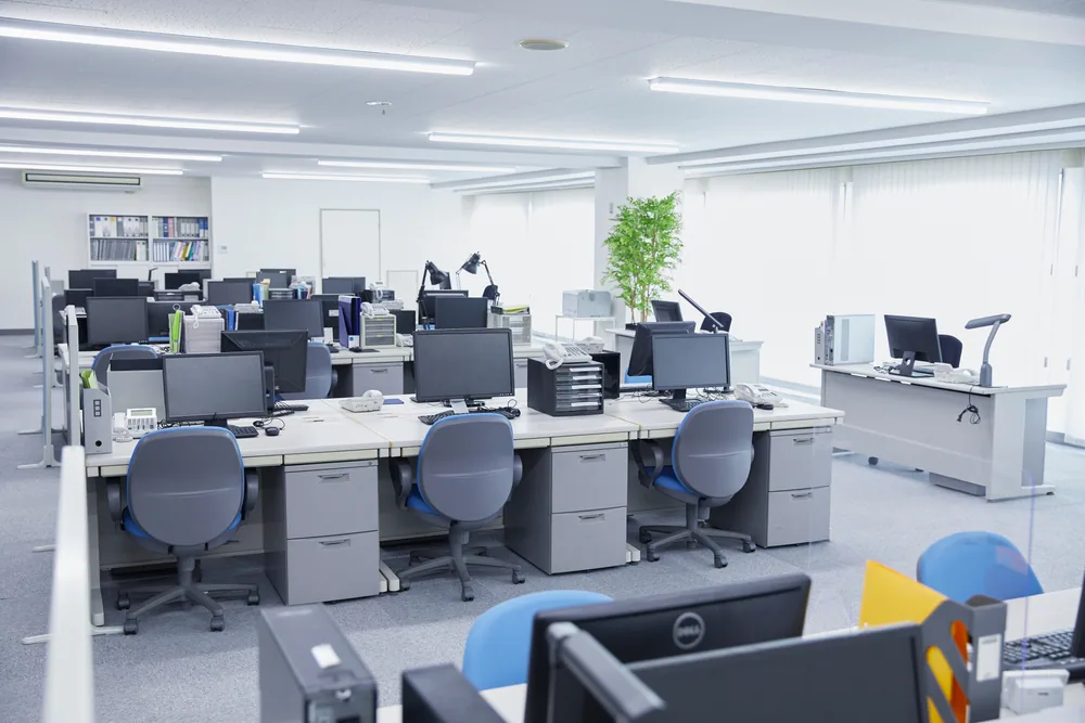 Oficina con mesas de monitores y torres de ordenador en cada puesto