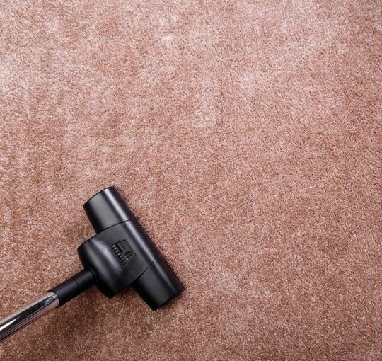 Vacuuming carpet with vacuum cleaner. Housework service. Close up of the head of a sweeper cleaning device.
